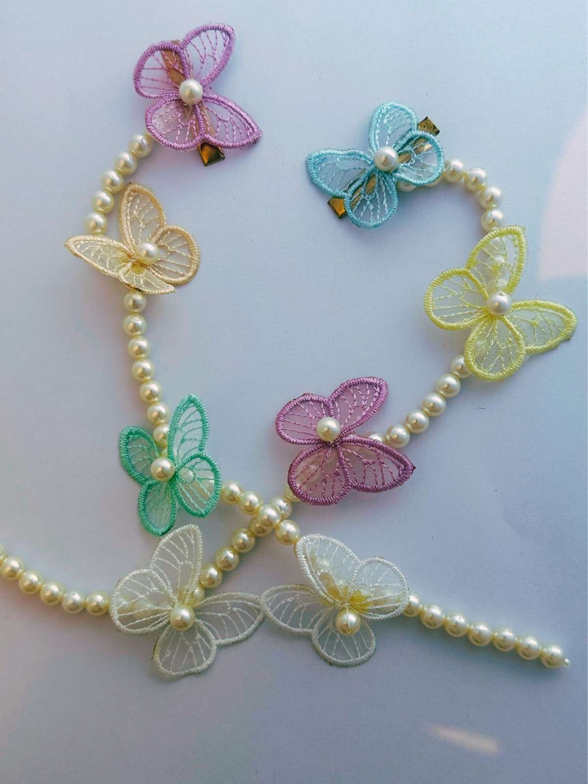 hair accessories with pearl beads and colorful butterfly charms on a light background