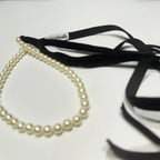 Pearl necklace with black ribbon on a white background
