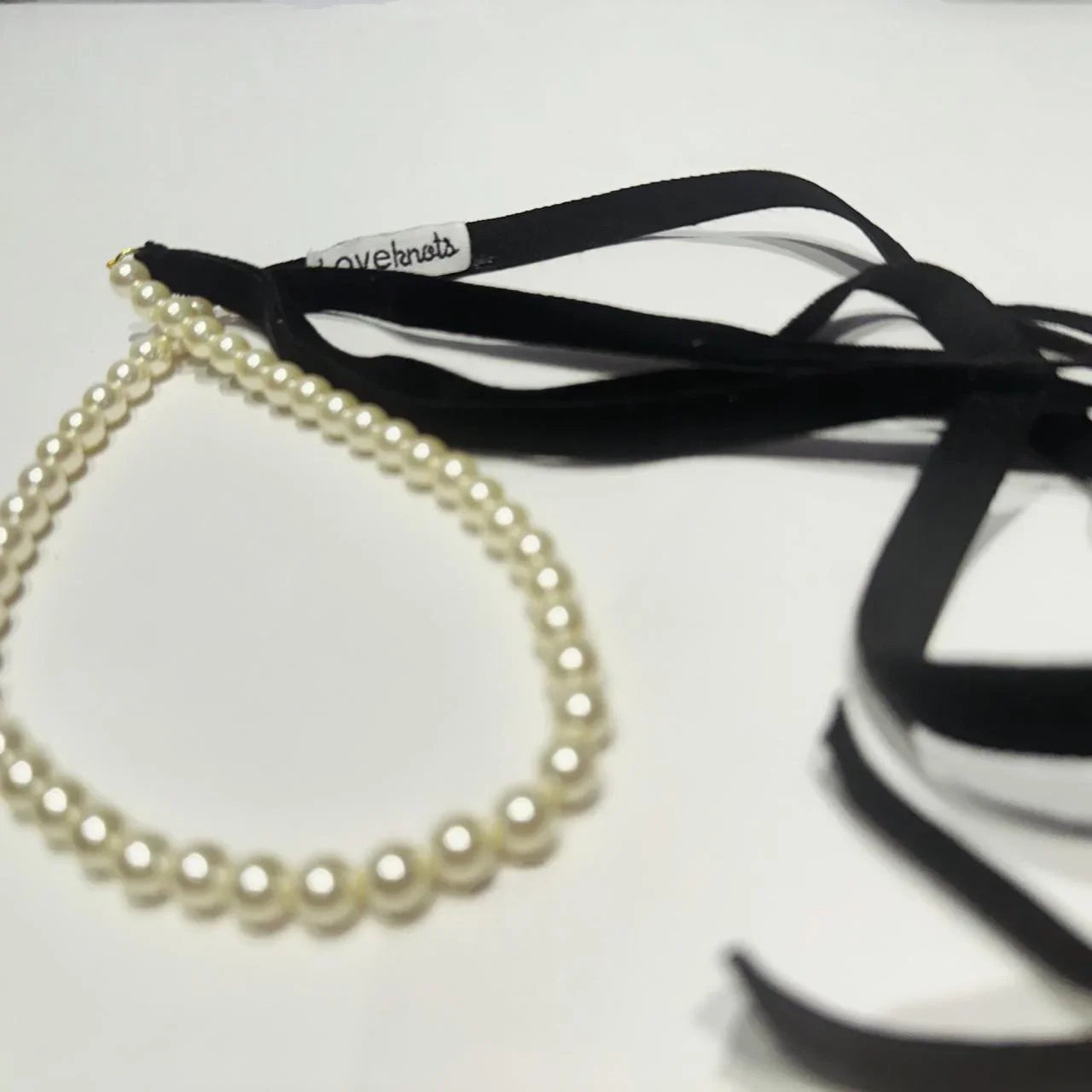 Pearl necklace with black ribbon on a white background