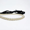 Pearl necklace with black ribbon , gold palated jump rings by loveknots on a white background