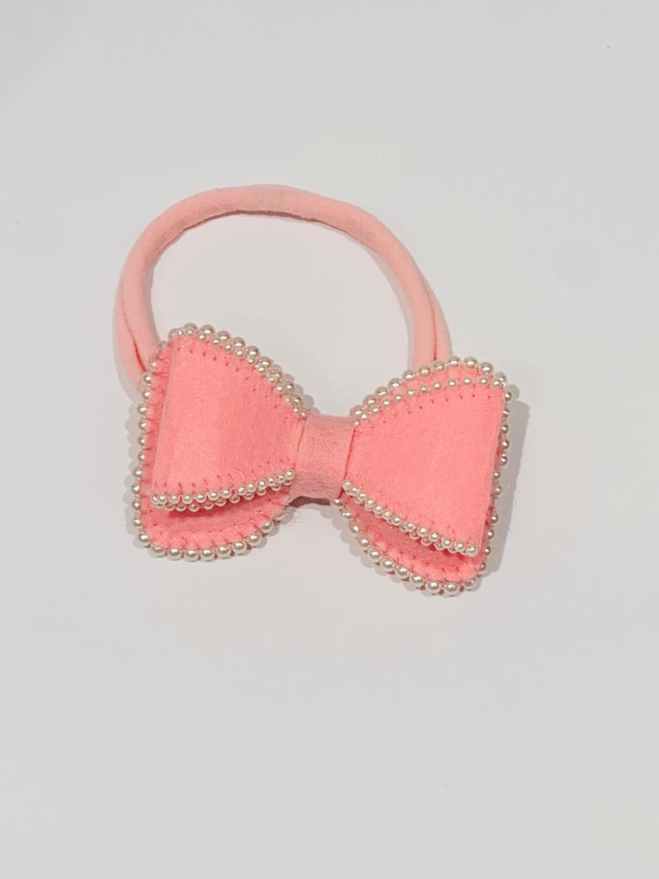Pink hair bow with pearl embellishments on a baby band
