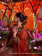 Woman in traditional attire with floral decorations and architectural elements in the background wearing pearl tassels ghungroo parandi by loveknots