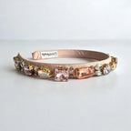 Decorative pink headband with colorful gemstones on a white background