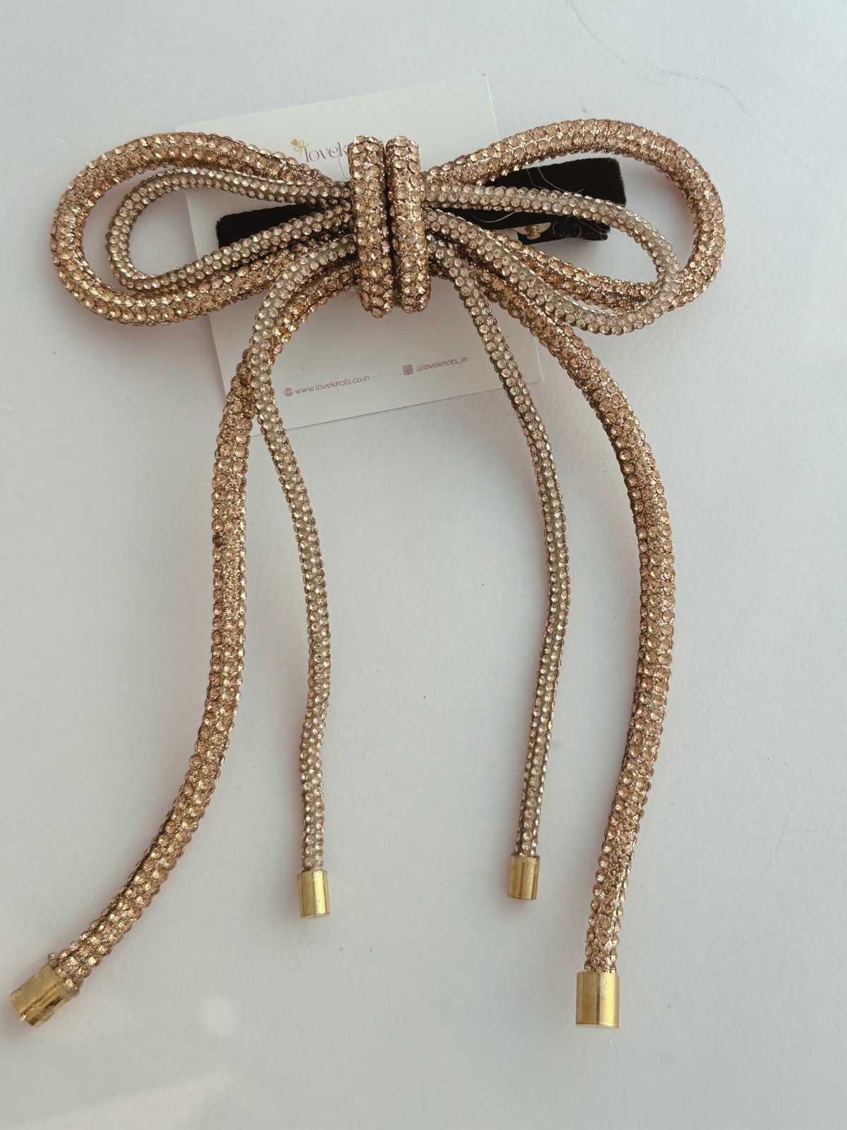 Gold bow-shaped hair accessory on a white background