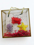 Set of colorful crab, octopus, and starfish toys in a clear gift box with gold handle by lovenots