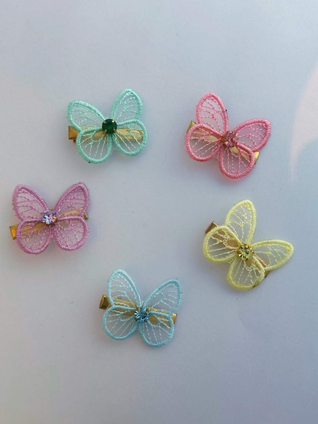 Five colorful butterfly-shaped hair clips on a light gray background