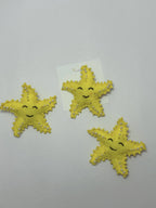 Three yellow star-shaped hair clips with pearl embellishments on a loveknots 