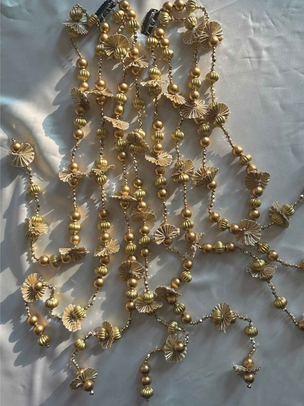 Gold beaded lateen parandi with floral elements on a white fabric background