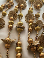 Close-up of ornate gold pearl parandi with intricate designs on a light background