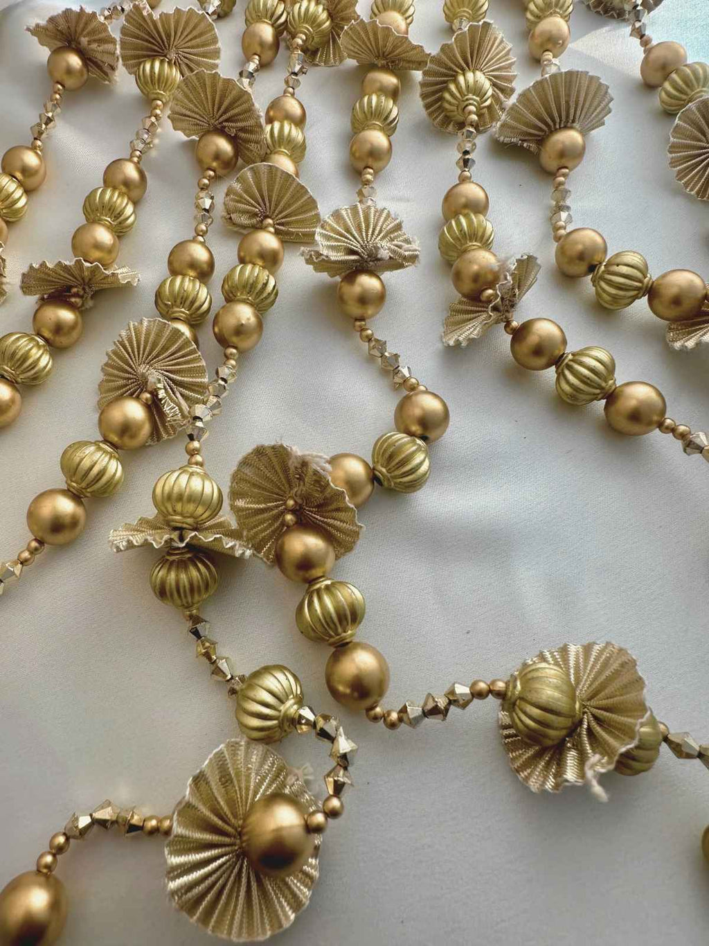 Close-up of a gold beaded parandi with decorative elements on a light background