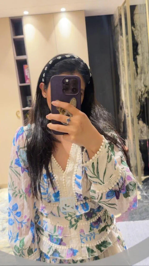 women wearing a floral outfit taking a mirror selfie in a room wearing black pearl hairband by loveknots
