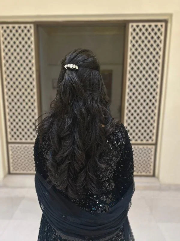 loveknots founder Srishti Bansal with long, dark hair styled in an elegant updo with a decorative hairpin, wearing a black outfit.
